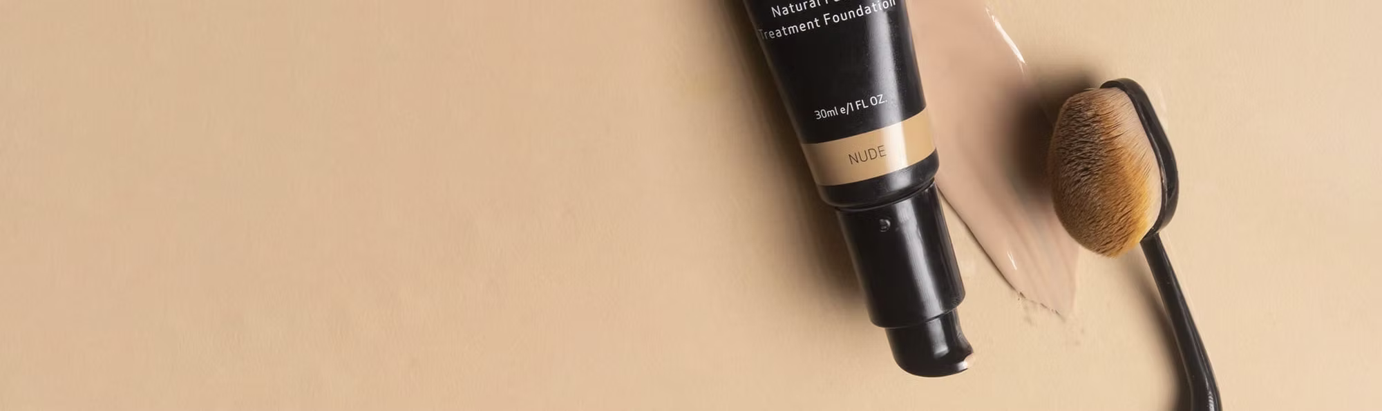 Foundation bottle with applicator on a beige background