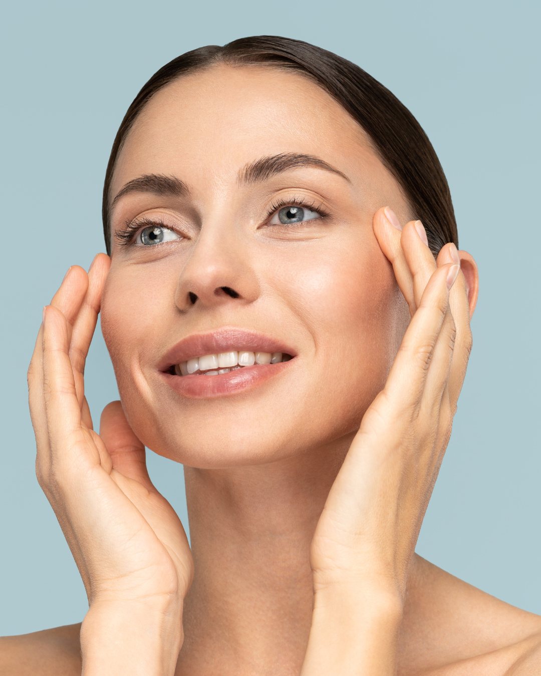 Woman touching her face against a light blue background