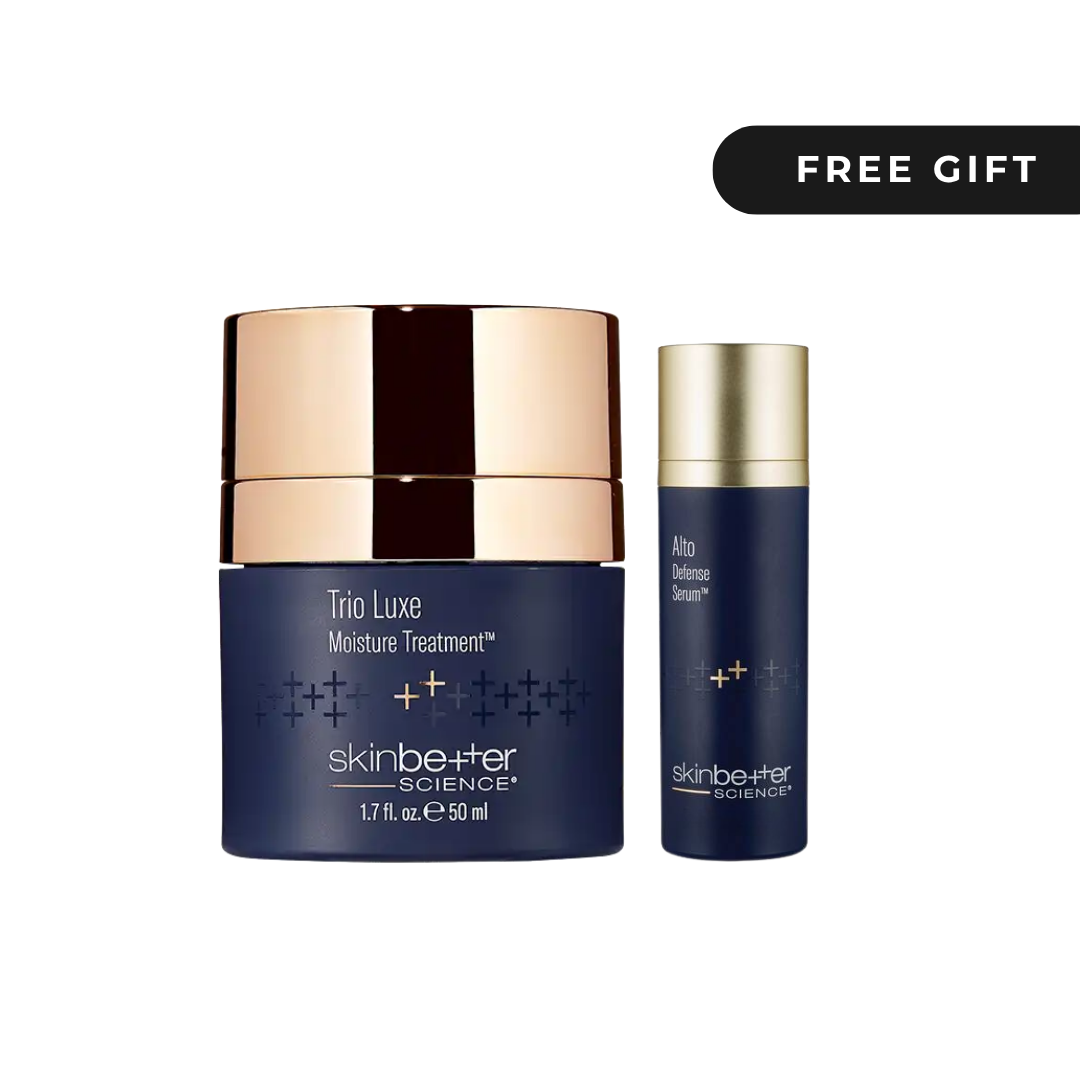 Skinbetter Science Trio Luxe Moisture Treatment jar in navy blue with a metallic rose gold lid, shown next to a smaller matching serum bottle. A black banner in the top right corner reads 'FREE GIFT'.